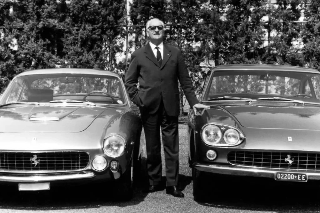 Enzo Ferrari, geboren am 18. Februar 1898, zwischen zweien seiner Sportwagen, einem Ferrai 250 GT Berlinetta und dem Ferrari 330 GT 2+2