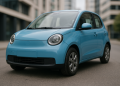 Kleiner blauer Elektro-Kleinstwagen in Frontansicht auf einer Stadtstraße